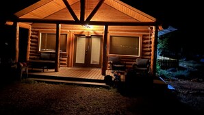A log cabin with a porch, two doors, and two windows. - Charming 2-bedroom cabin with bonus loft, pet-friendly in Seeley Lake (Seeley Lake)
