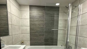 Ein modernes Badezimmer mit einer Badewanne, einer Toilette und einer Dusche.