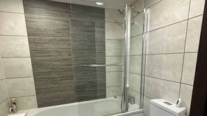 A modern bathroom with a glass-enclosed shower, a white bathtub, and a toilet. - 1br-sleeps4-parking-closetocentre (Birmingham)
