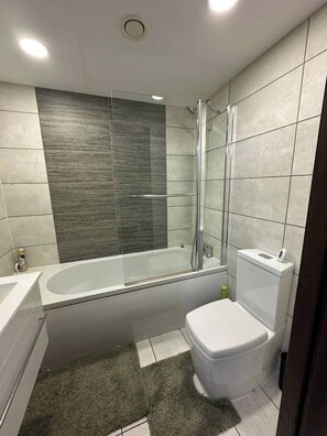 A modern bathroom with a glass-enclosed shower, a white bathtub, and a toilet. - 1br-sleeps4-parking-closetocentre (Birmingham)