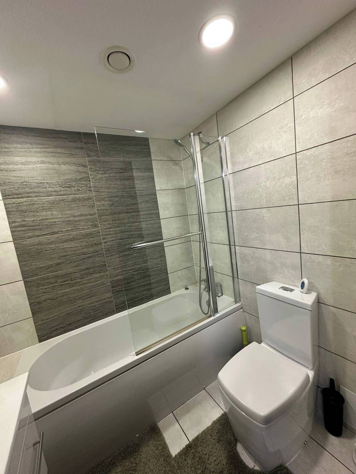 A modern bathroom with a glass-enclosed shower, a white toilet, and a bathtub.