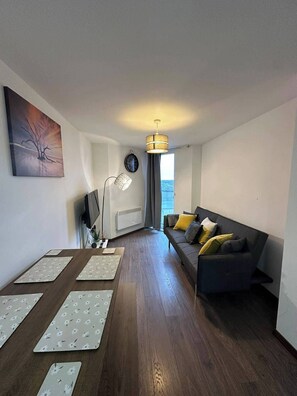 Un salon moderne avec un canapé foncé, une table basse, un lampadaire et un tableau accroché au mur.