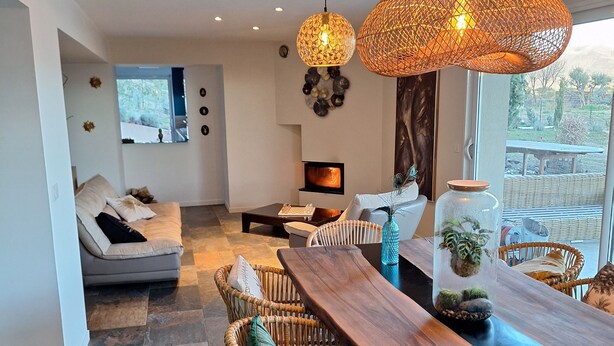 A modern living room with a wooden dining table, wicker chairs, a fireplace, and large windows. - Villa with pool in the heart of Provence, Pets welcome (Montfort)