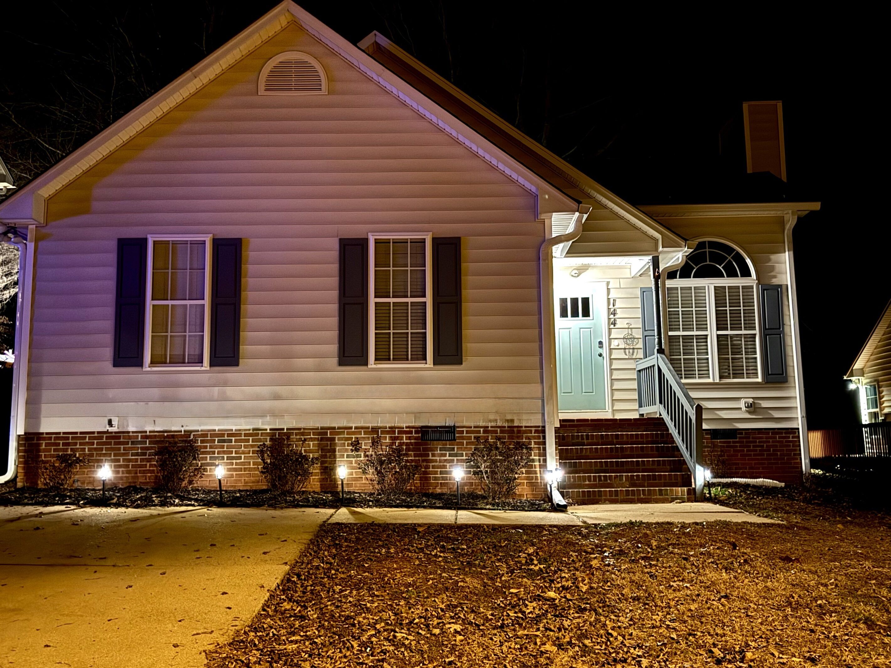 A two-story house with a front porch and a visible number '144' on the door.
