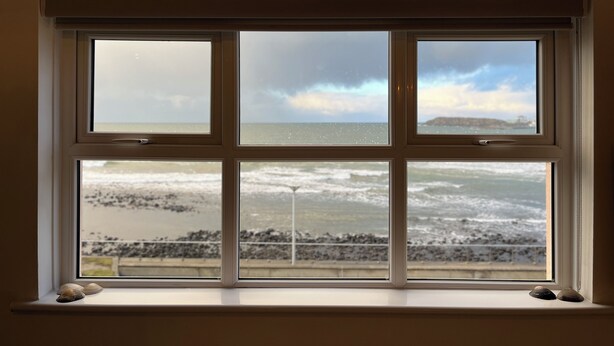 Ein Fenster mit Blick auf das Meer und eine felsige Küste.