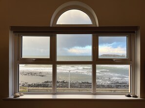 Una ventana con vista al mar y a la costa rocosa.
