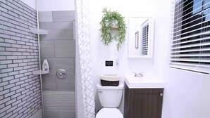 Ein Badezimmer mit Toilette, Duschbereich, Waschbecken und Spiegel.