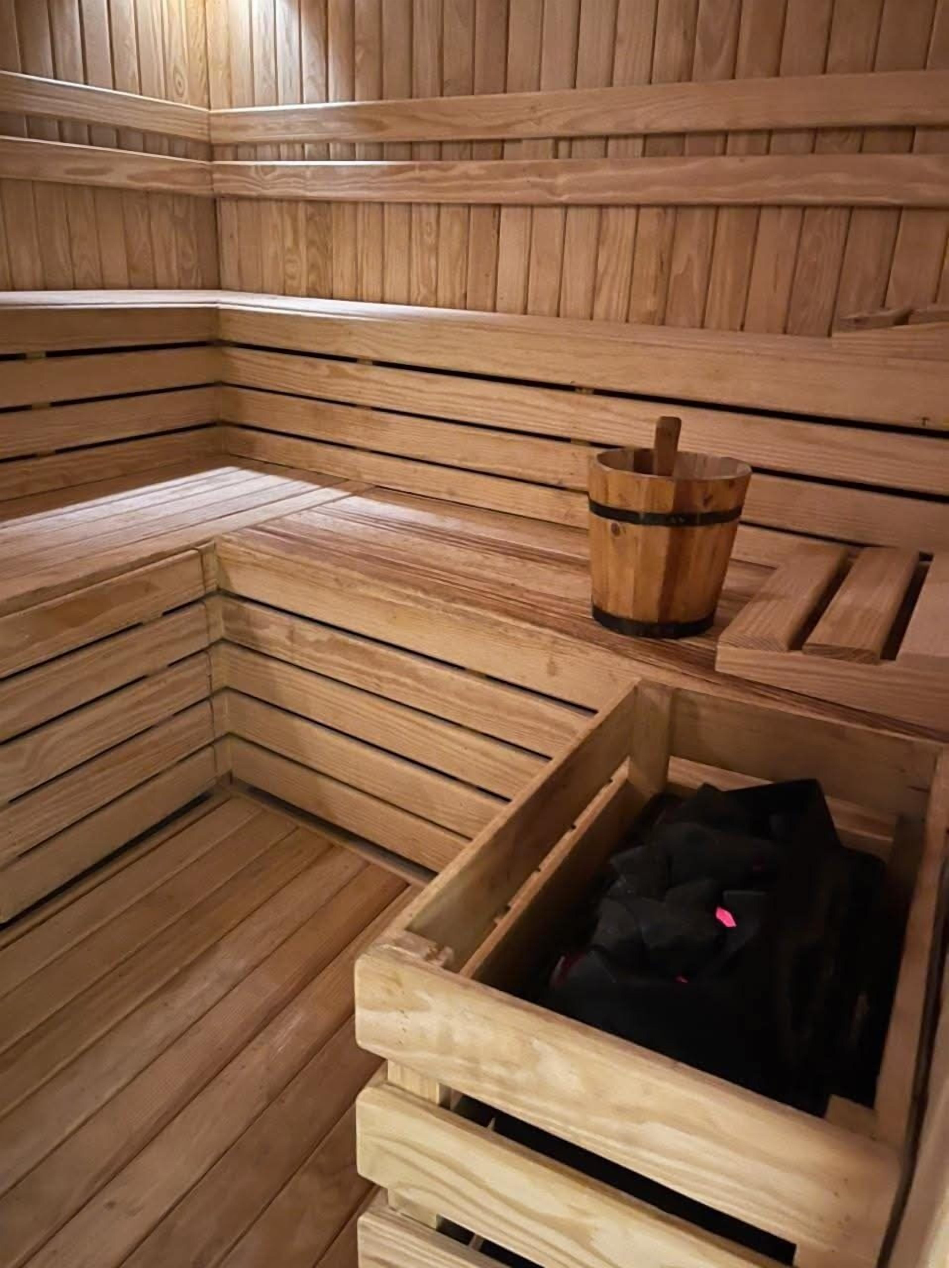 A sauna with wooden benches and a wooden bucket.