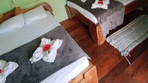 A room with two wooden beds, each with a grey bedspread and white pillows, and a ceiling fan above. - Caribbeans beach Cahuita (Beach house.) Near beaches, Houses in lemon. (Cahuita)