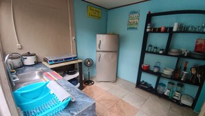 A compact kitchen with a sink, stove, refrigerator, and a shelf with kitchenware. - Caribbeans beach Cahuita (Beach house.) Near beaches, Houses in lemon. (Cahuita)