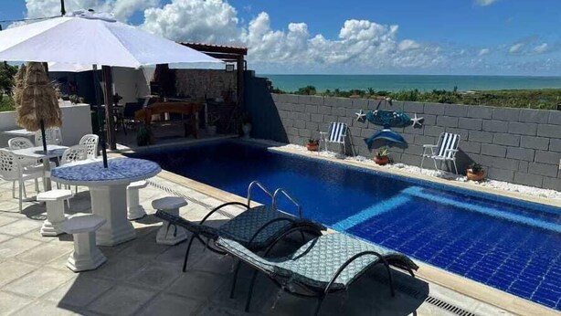 A pool area with lounge chairs, a table, and a covered seating area. - FLATS  PEQUENO PARAISO (Pitimbu)