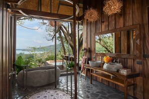 A bathroom with a stone sink, a large mirror, and a bathtub.
