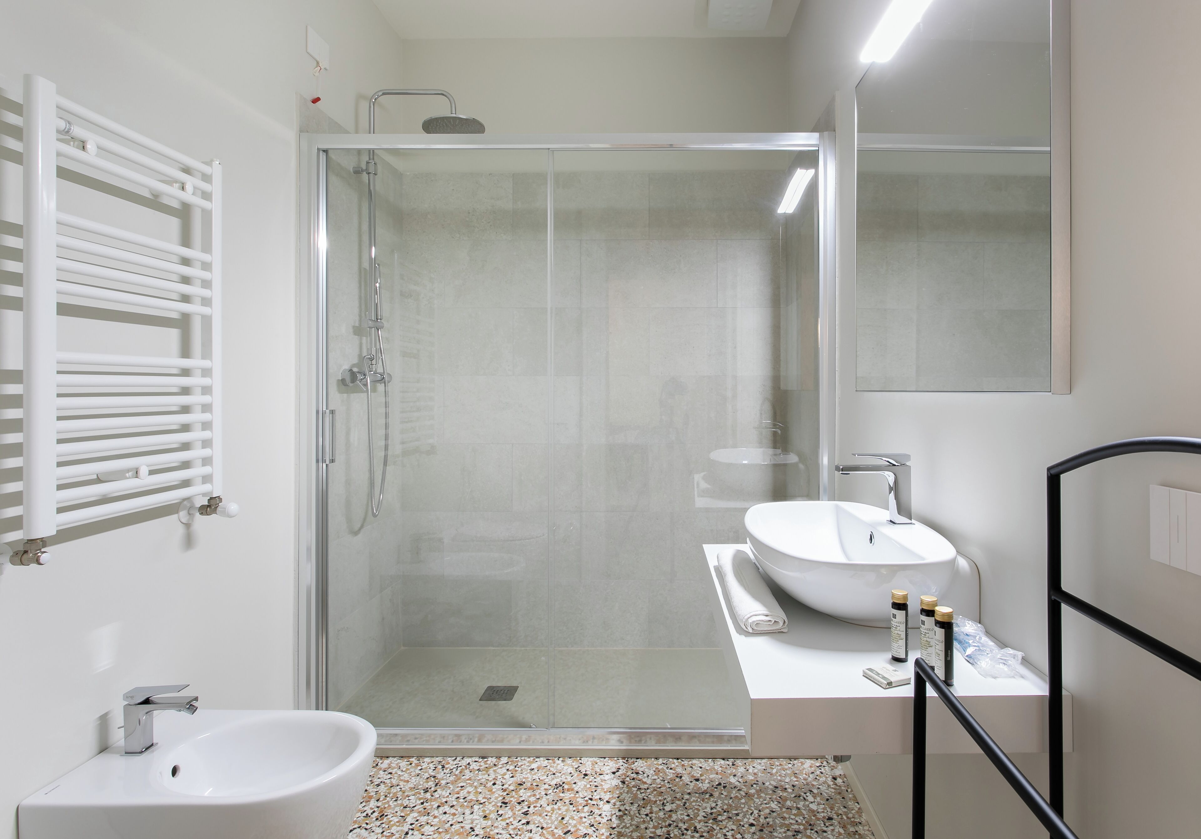 Un baño moderno con ducha de vidrio, lavamanos blanco y espejo grande.