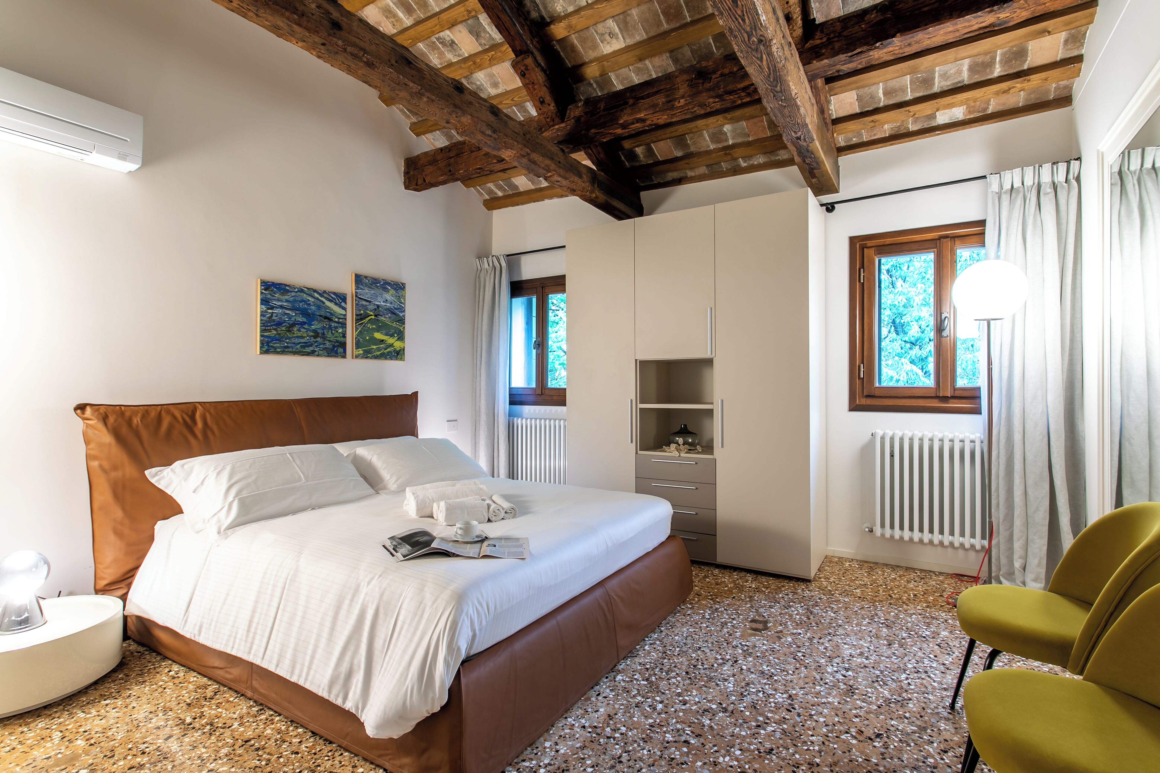 A bedroom with a bed, bedside table, lamp, and a chair.