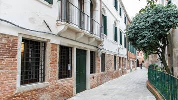 A narrow cobblestone street flanked by historic buildings with brick facades and green shutters.