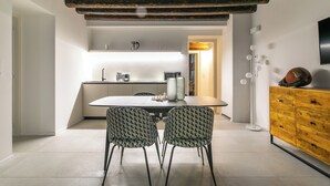 Een moderne keuken met een centraal eiland, twee gestreepte stoelen, een houten kast en een flatscreen televisie aan de muur.