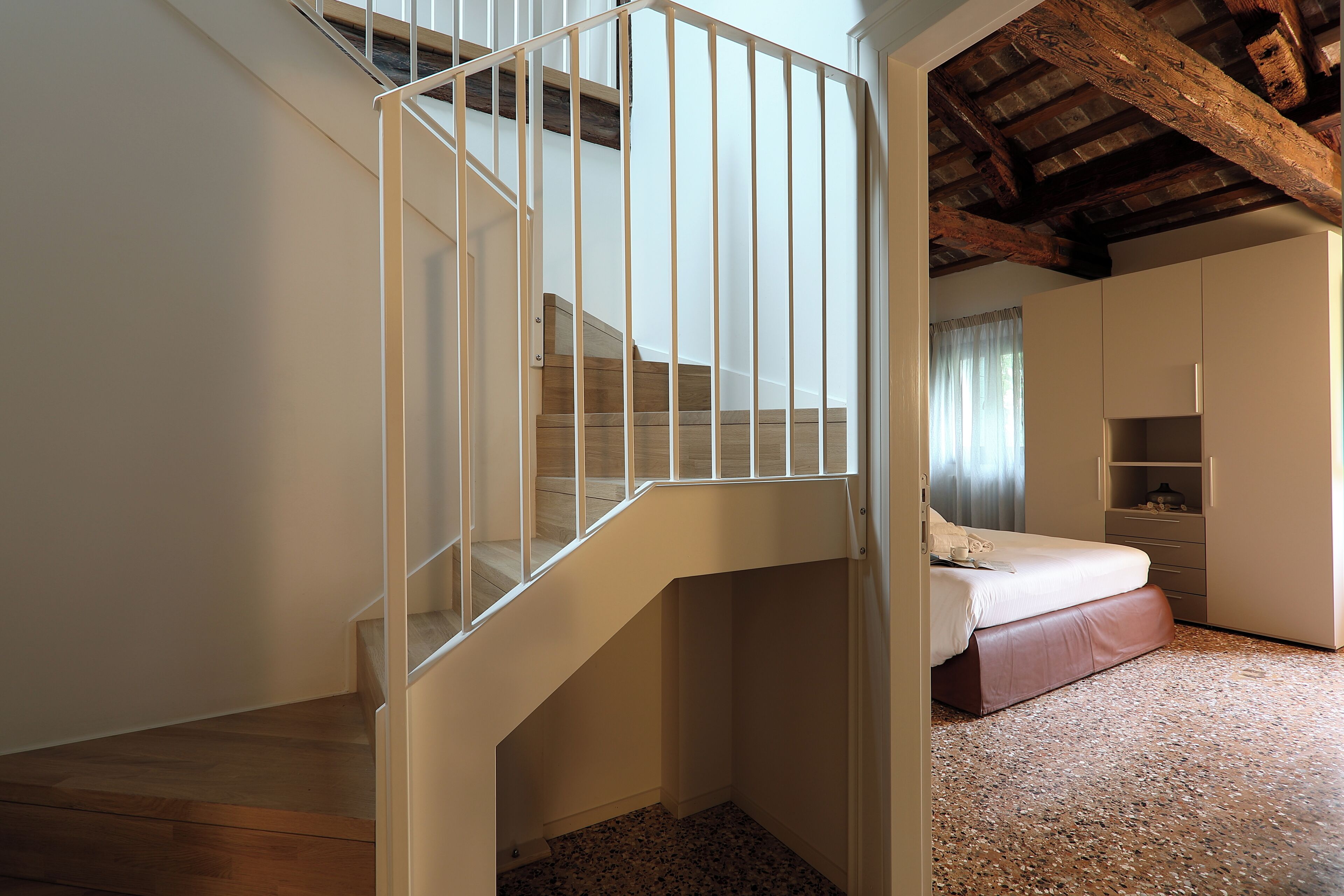 Une chambre avec un escalier en bois, un lit et des étagères intégrées.