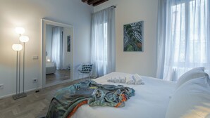 Een slaapkamer met een groot bed, een spiegel, een stoel en een schilderij.