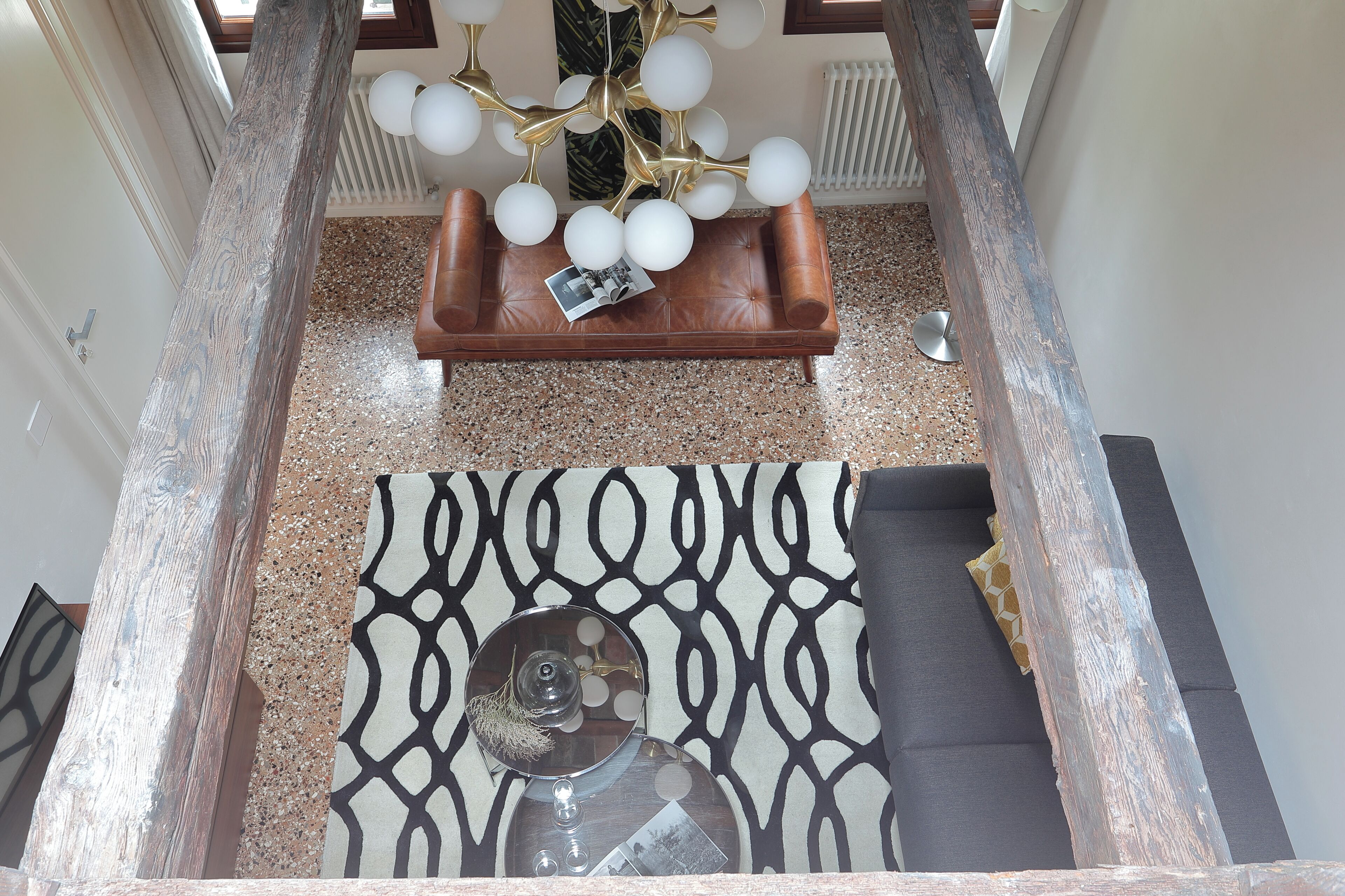 Um interior moderno com um sofá de couro, um tapete estampado e um candelabro único.