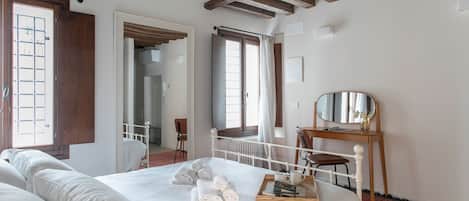 Ein Schlafzimmer mit einem großen Bett, einem Holztisch, einem Spiegel und Blick auf einen Balkon.
