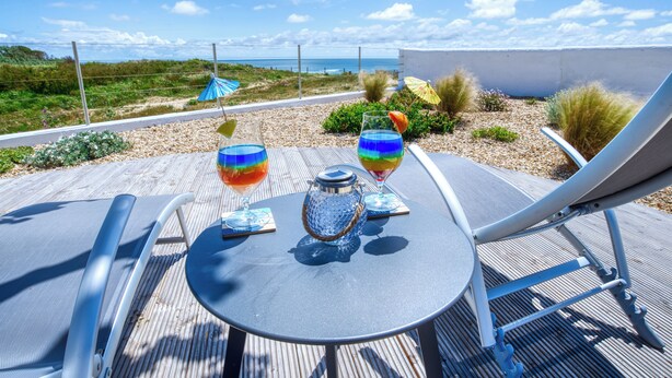 Une terrasse avec une table, deux chaises et deux boissons colorées.