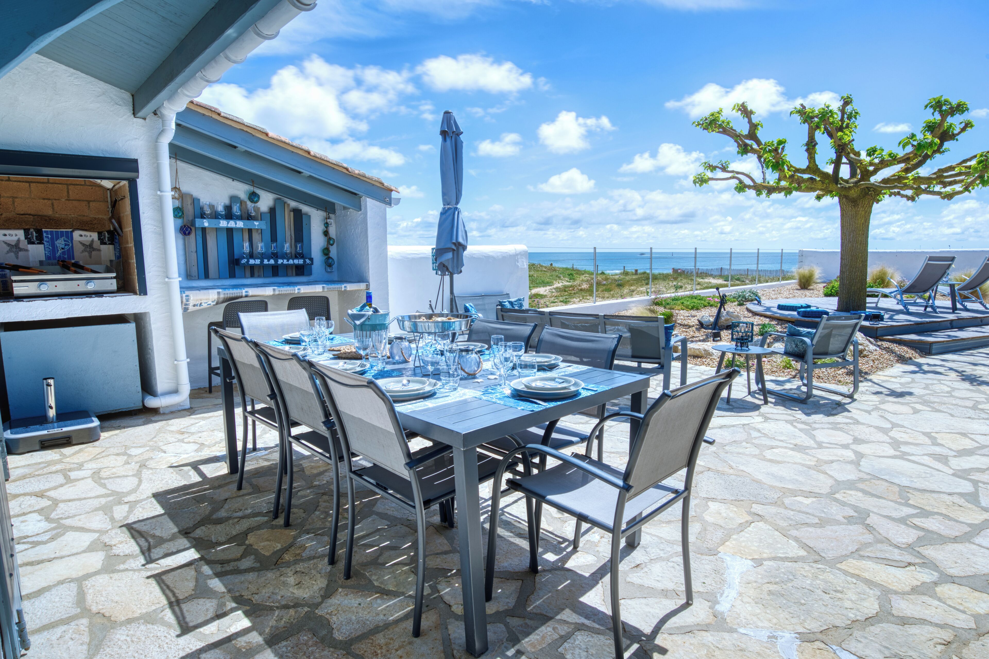 An outdoor dining area with stone flooring, metal chairs, and a bar counter.