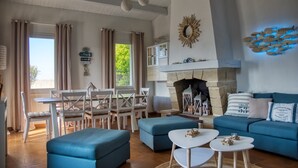 Un vaste espace de vie comprenant une cheminée, un ensemble de salle à manger et un canapé bleu.