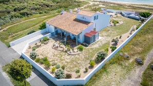 Une propriété située sur la côte, comprenant une grande maison dotée d’un toit en tuiles, d’une piscine et d’un jardin clôturé.