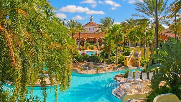 A resort with a swimming pool, palm trees, and a large building with a red roof.