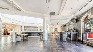 A spacious hotel lobby with a central bar area, a stone accent wall, and a view of the outdoor area.
