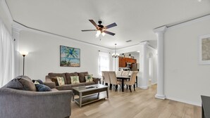 A spacious living room with a gray sofa, a coffee table, and a dining area with a table and chairs.