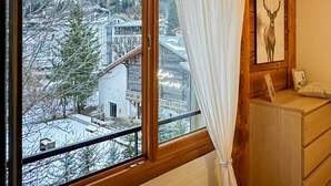 Una habitación con un ventanal grande, un aparador de madera y un cuadro enmarcado con un ciervo.