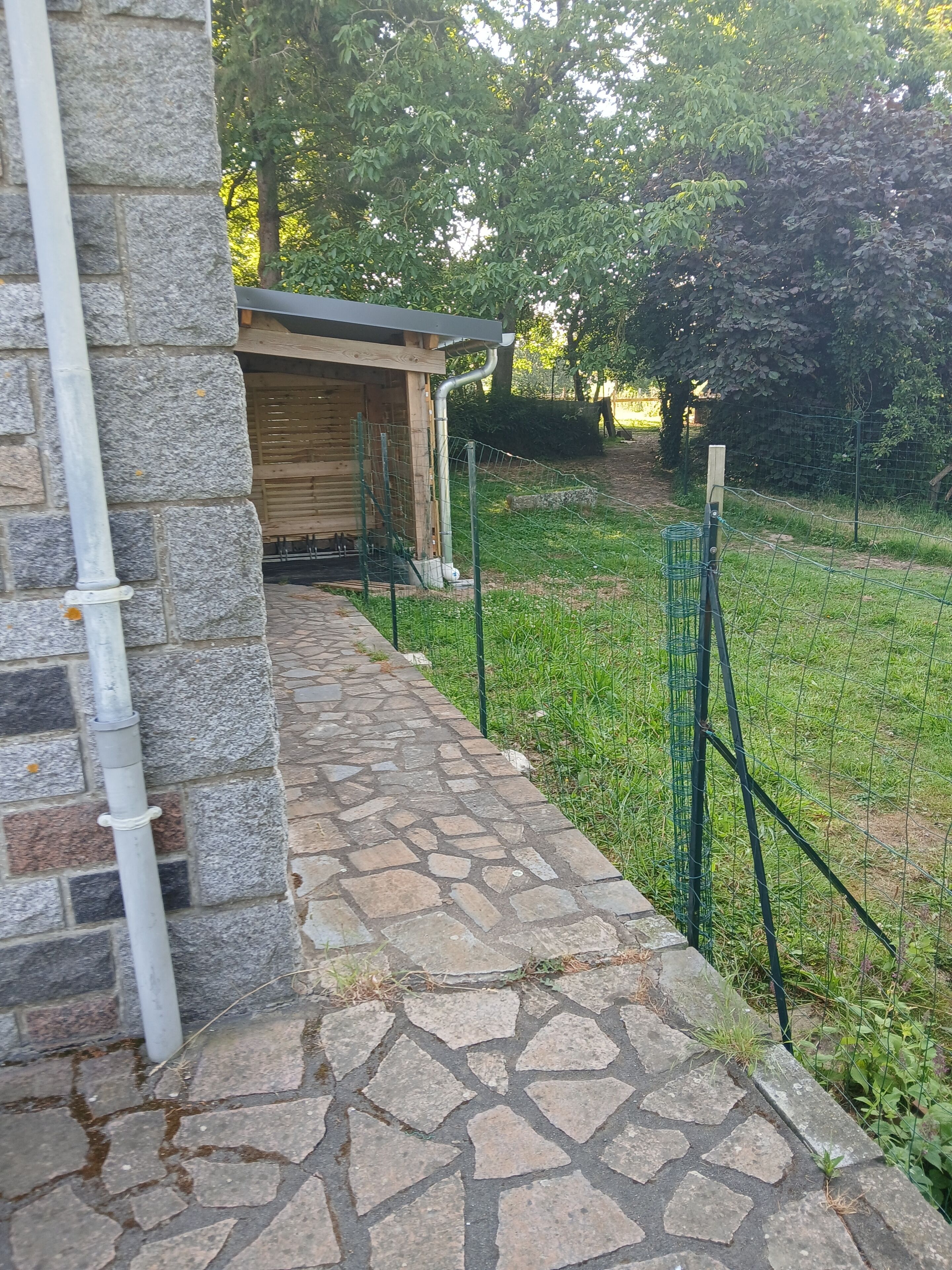 Un camino empedrado que conduce a una estructura de madera con una cerca metálica.