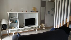 Een woonkamer met een televisie, planken, een lamp en een stoel.