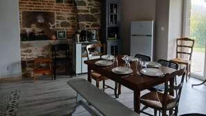 Een eetgedeelte met een stenen muur, een koelkast en een tafel gedekt voor vier personen.