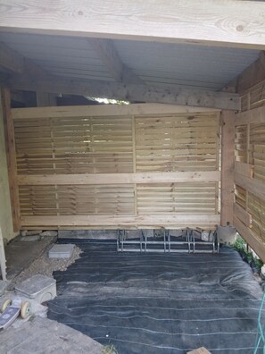 Eine Holzkonstruktion mit einer durchbrochenen Wand, einem dunklen Teppichboden und einem kleinen weißen Behälter.