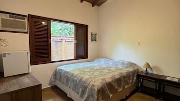 Cozy retreat with a bed centered in the room, flanked by a window and air conditioning unit.