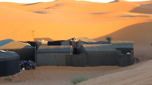 A desert camp with tents and a dune buggy. - Merzouga Traditional Camp (Taouz)