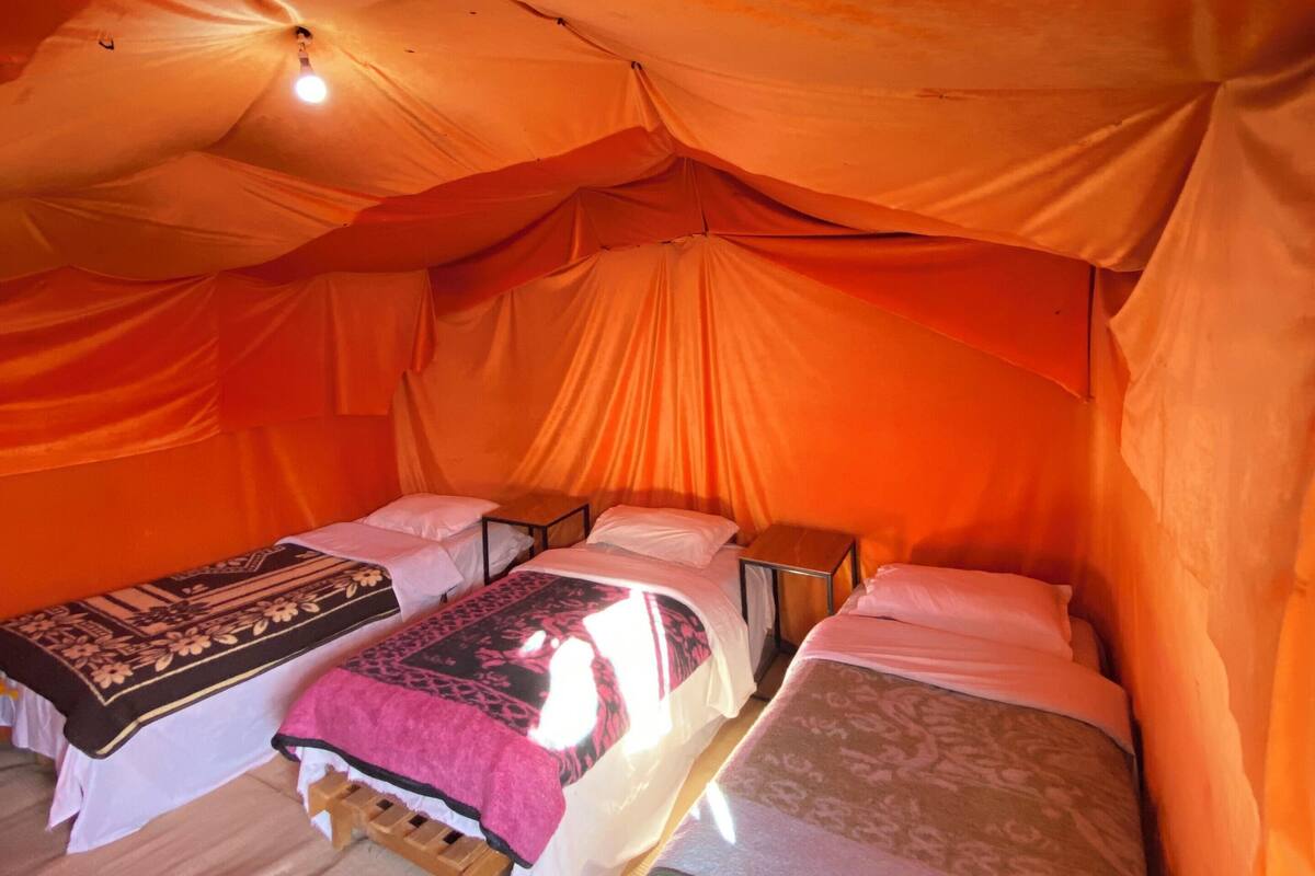 A tent with two beds, each with a pillow and a blanket.