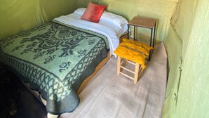 A tented room with a bed, a small table, and a chair. - Merzouga Traditional Camp (Taouz)