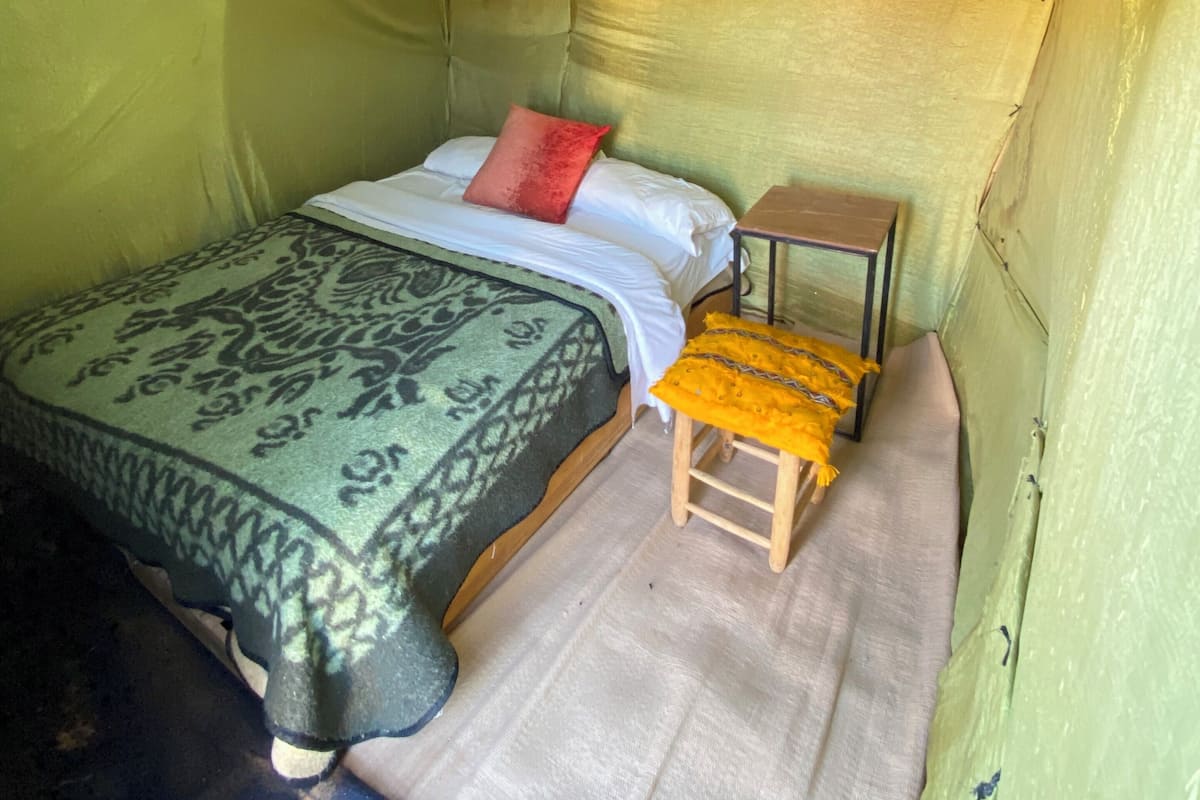 A tented room with a bed, a small table, and a chair.