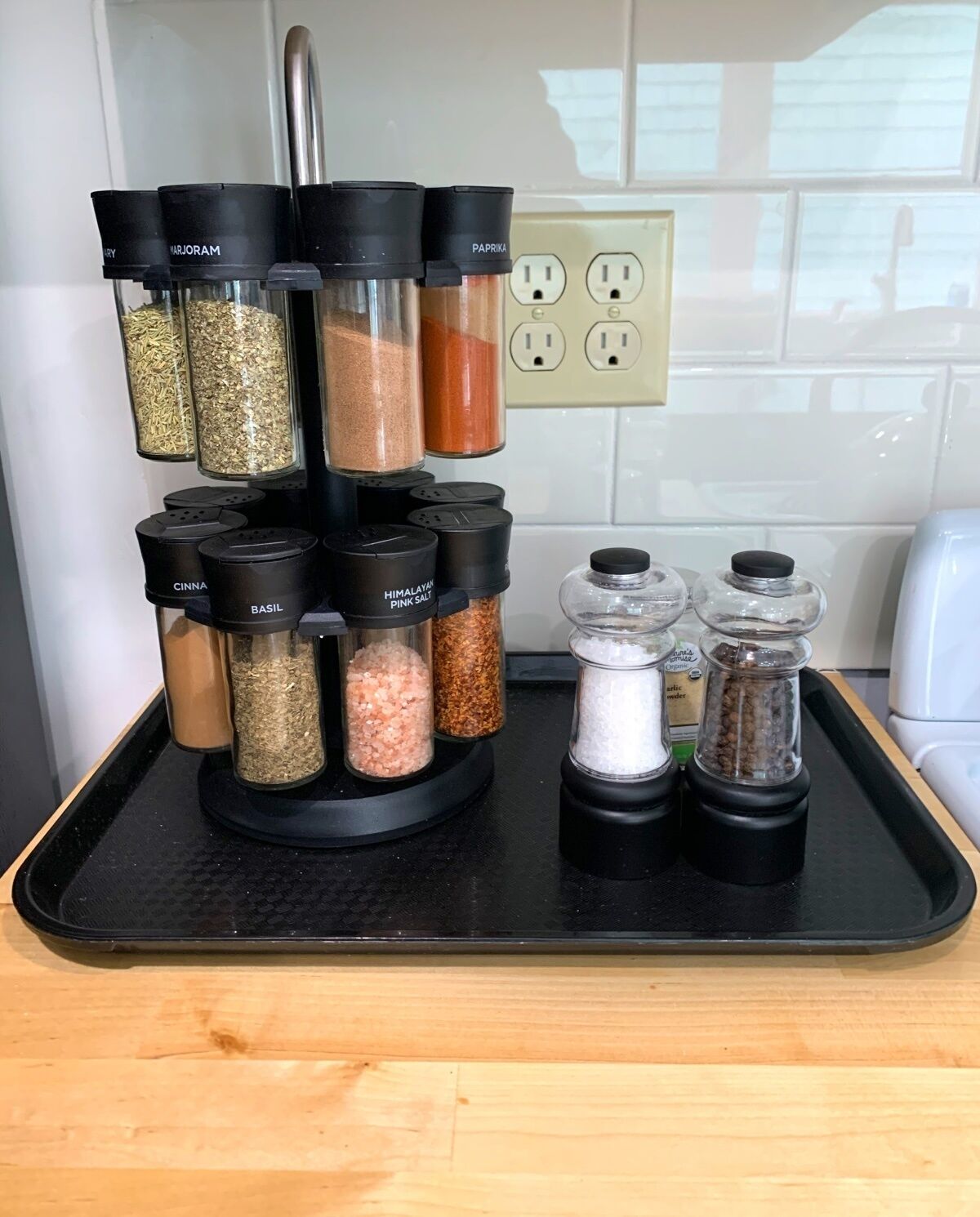 A spice rack with labeled containers on a kitchen counter.