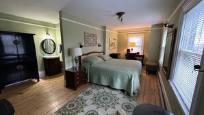 A bedroom with a bed, dresser, nightstand, lamp, and a window with blinds. - The Northport Inn & Lodge (Belfast)