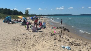 Une plage de sable où l’on voit des gens se détendre, des tentes et des chaises de plage.
