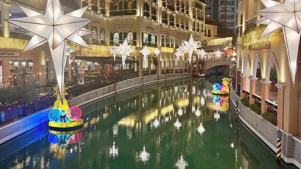 A hotel with a canal, star-shaped decorations, and a boat with colorful lights.