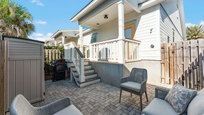 Une maison dotée d’un patio couvert, d’un espace salon extérieur et d’une clôture en bois.