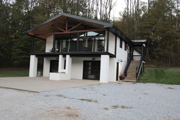 A modern two-story building with a covered porch, large windows, and a staircase leading to an upper level.
