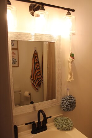A bathroom with a white sink, black faucet, and a mirror with a light fixture above it.