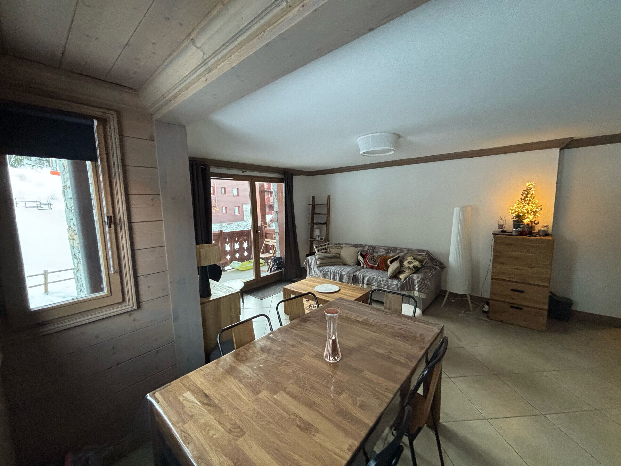 A cozy living room with a wooden dining table, a sofa, and a dresser.