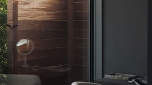 Una habitación moderna con un ventanal grande, una separadora de madera y una zona de estar con una mesa y sillas.